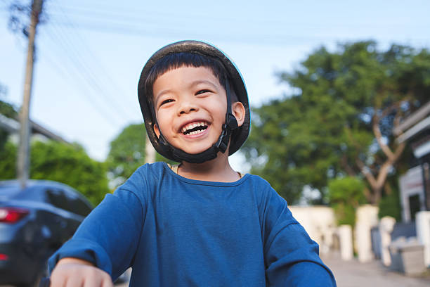 Happy little boy seated on a yellow bumper car, navigating a paved surface within an outdoor recreational setting.\nShot with Nikon D850