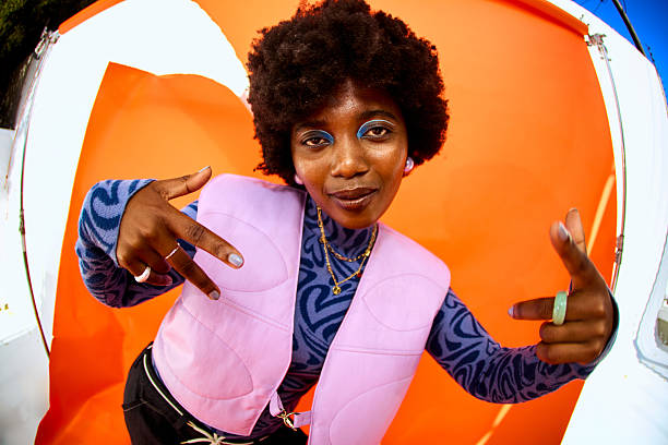 Young woman styling y2k fashion posing in studio with orange background