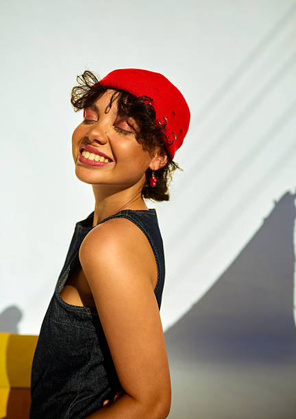 Joyful woman in red hat and denim top feeling wellbeing in studio