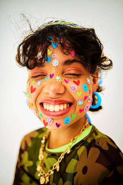 Young adult woman expressing joy with fun face stickers on a white background
