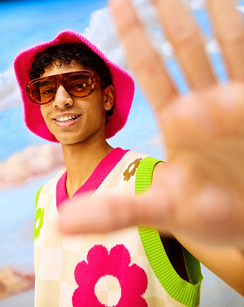 Young man smiling while reaching hand out to camera in casual retro outfit
