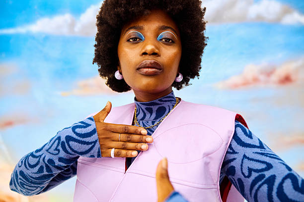 Young black woman expressing creativity with bold makeup and pastel fashion in a studio