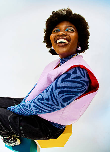 Young adult black woman laughing cheerfully, expressing joy and freedom in a bright studio