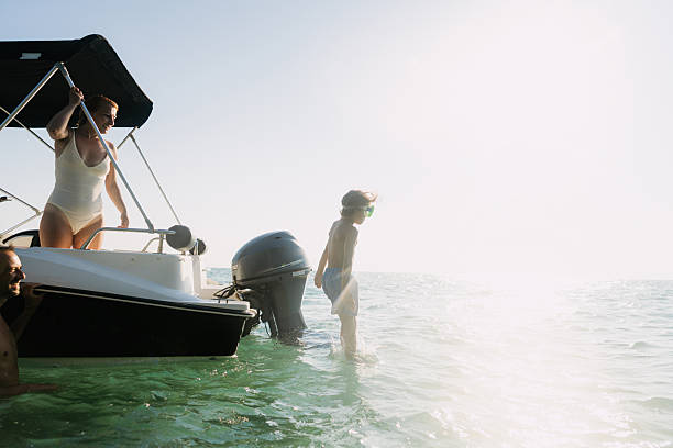 Photo of a cheerful young boy, enjoying a summer day on the boat with his mom