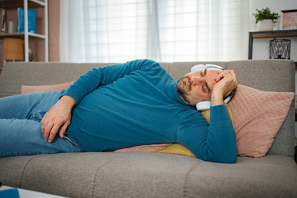 Man sleeping on a couch wearing headphones, finding comfort and relaxation at home