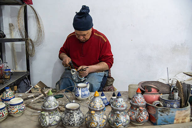 A skilled artisan shapes and fires colorful Moroccan ceramic jars in a cozy studio. The scene showcases traditional pottery, intricate patterns, and a focused craftsman at work.