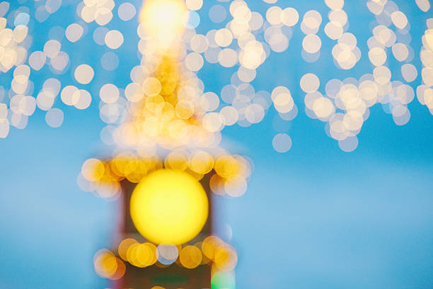 Glowing soft yellow and white circular lights on a dreamy blue background creating a festive blur.