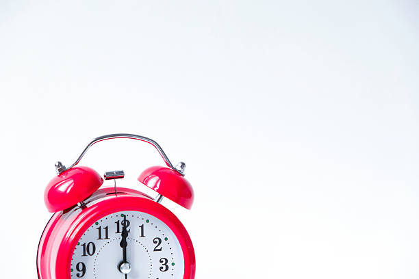 The classic red alarm clock is isolated on a white background