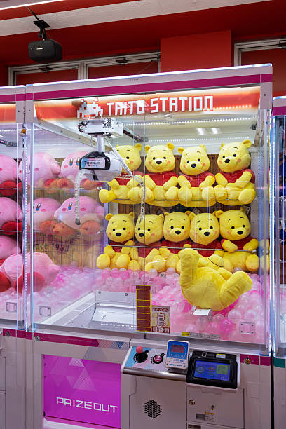 Osaka, Japan - March 30, 2025: Closeup of Winnie the Pooh plush toys in Arcade claw Taito station machine in in Osaka, Japan