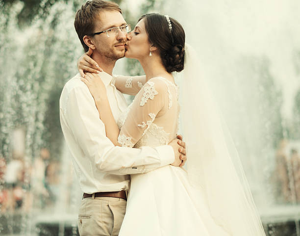 Bride with white wedding dress playing with the water of a fountain