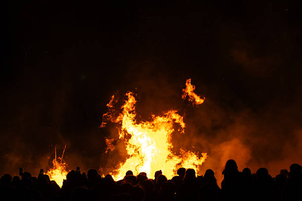 A crowd of people watching a giant bonfire.