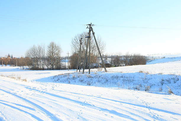 A snowy field with power lines. Snow. Outdoor. Sky. Covered. Nature