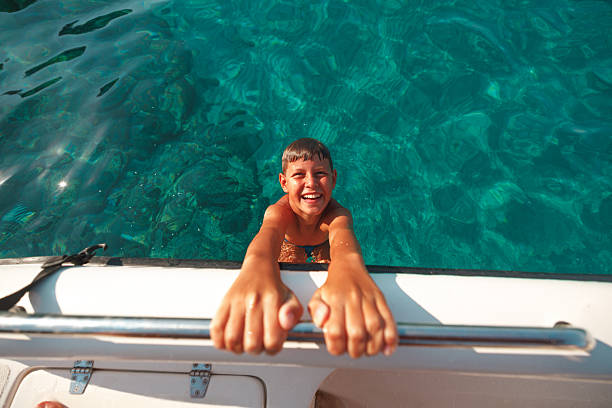 Young boy wearing blue shorts swimming and playing in a pool on a sunny day