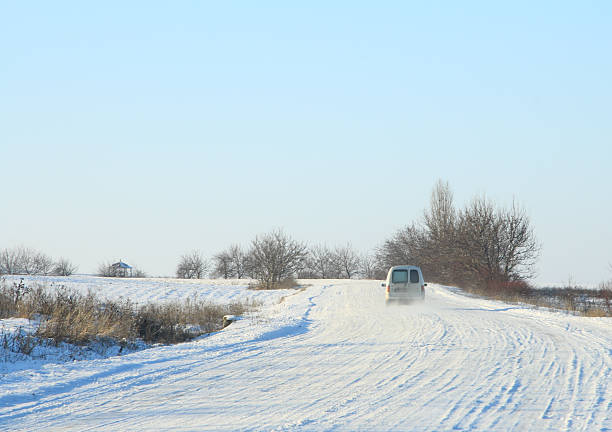 A car driving on a snowy road. Snow. Sky. Outdoor. Nature. Day
