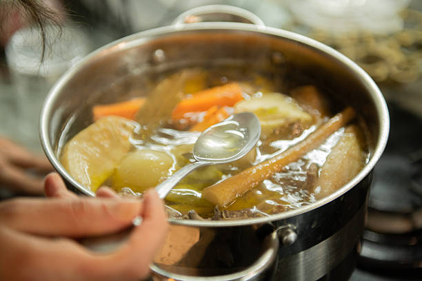 Pot with vegetables cooking on a stove in a home kitchen. Homemade meal preparation and healthy cooking concept.