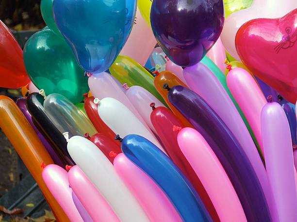 Brightly colored balloons, including red, blue, and green, set against a city street background.