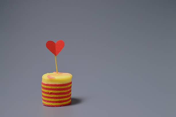 Delicious cake and paper heart on a gray background
