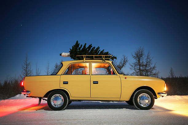 Yamal, Russia - January 2, 2026: Soviet classic car Izh-Moskvich-412IE-028 with the Christmas tree on the roof boot in the snow covered tundra at night.