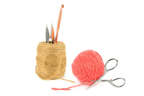 Elegant craft supplies including silver scissors and a copper hook on white. Ideal for needlework tutorials and hobbyist magazines.