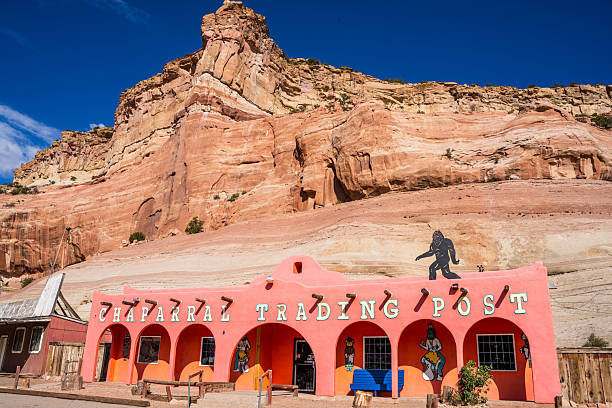 CONTINENTAL DIVIDE, NEW MEXICO, USA - SEPTEMBER 10, 2029: The colorful storefront of the Chief Yellowhorse Trading Post stands against massive red sandstone cliffs. Located on historic Route 66 near the Arizona border, this iconic roadside attraction features signs for Navajo and Zuni jewelry and buffalo jerky, representing the enduring spirit of Native American commerce and Americana along the Mother Road.