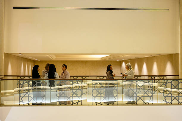 Professional women engaging in conversation and networking on an elegant balcony of a modern building, featuring striking geometric patterns on the railings and warm lighting