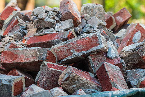 Closeup shows discarded red bricks sitting piled up in a dumpster at a construction site.