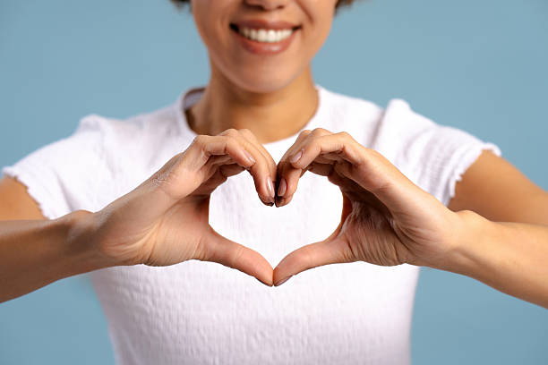 istock Smiling woman showing heart shape with hands selective focus on hands isolated on blue background 2257110607
