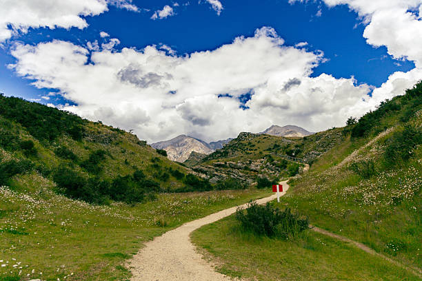 Curving route leads toward distant rocky hillsides path dirt track hillside