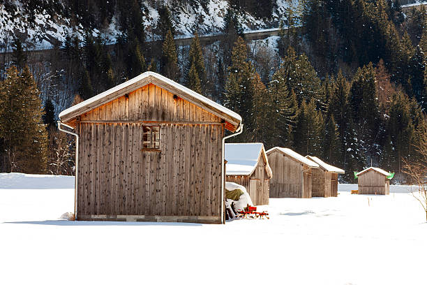 Snow covered sheds and forests in the mountains in winter on a sunny day in Austrian Alps.