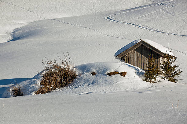 Snow covered shed in the mountains in winter on a sunny day, Austrian Alps