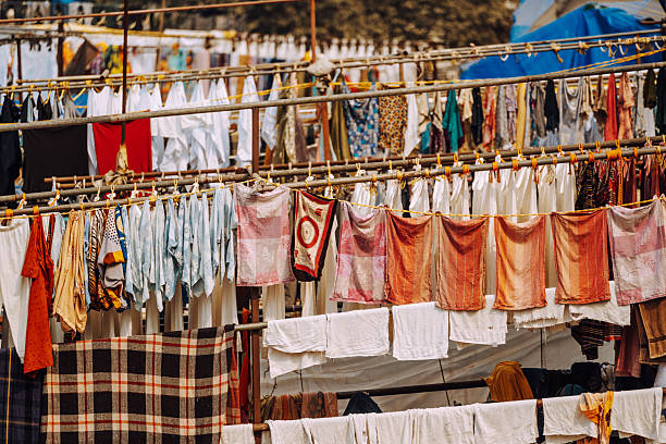 Vibrant rows of clothes and fabrics hang on drying lines across a bustling Mumbai street market, capturing daily life, color, and the lively urban atmosphere of Indian neighborhoods.