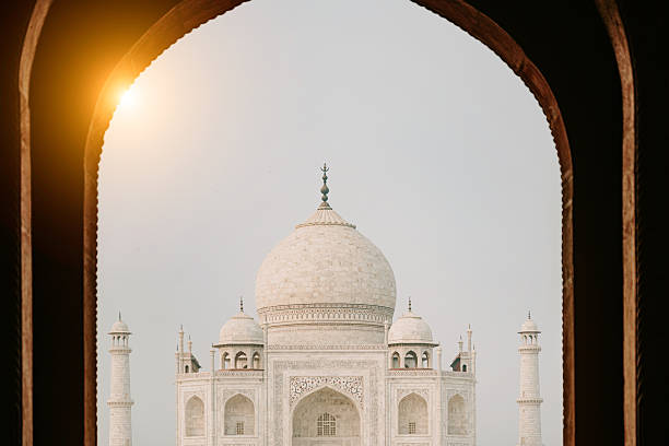 Majestic Taj Mahal framed by an ornate arch, bathed in warm sunrise light. A serene, historic monument scene highlighting architecture, heritage, and travel wonder in India.