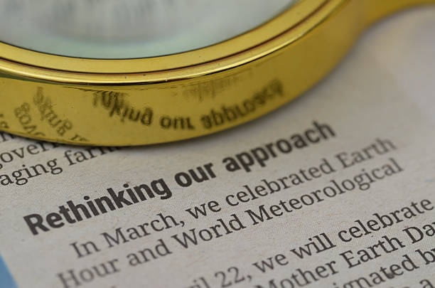 A magnifying glass rests on top of a downward sloping chart with the word stagflation on top of it.