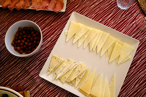 Assorted gourmet cheeses including hard and soft types like Morbier, Tomme, Comté, and Camembert, displayed for rustic food and culinary stock photography.