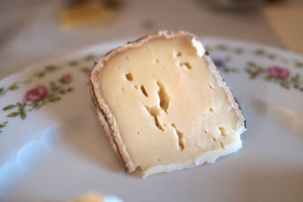 Assorted gourmet cheeses including hard and soft types like Morbier, Tomme, Comté, and Camembert, displayed for rustic food and culinary stock photography.
