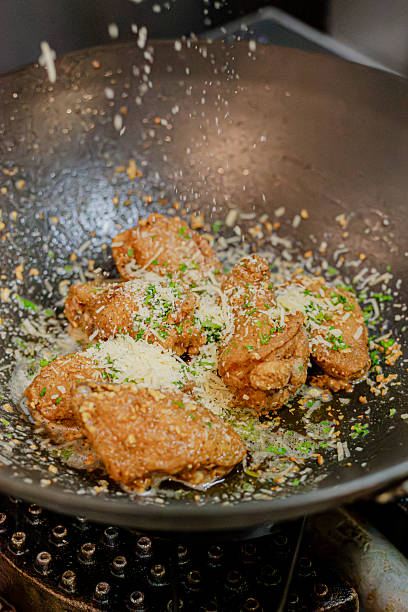 Chicken Cooking in Skillet Topped with Parmesan Cheese and Fresh Herbs