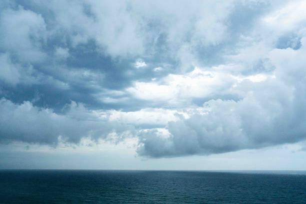 dense storm clouds advancing over the sea in daylight, capturing the tension and power of approaching coastal weather along a rugged shoreline