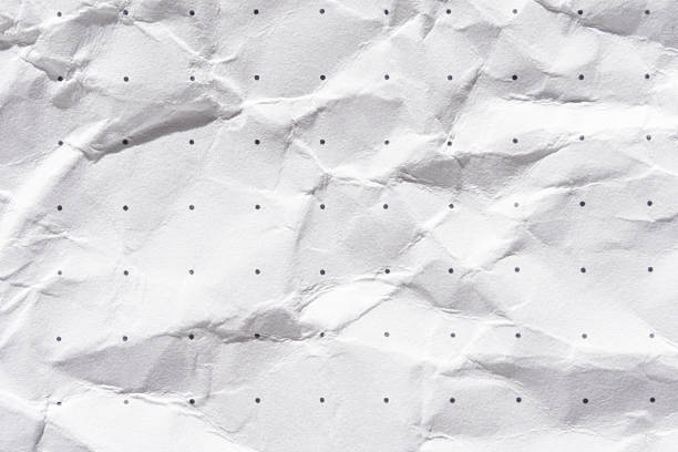 Crumpled white paper with dotted pattern texture for abstract background design concepts.