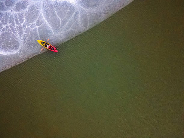 Person in colorful kayak navigating the edge of frozen ice & open water, combining extreme sports adventure with beauty of nature. Explorer on discovery travel