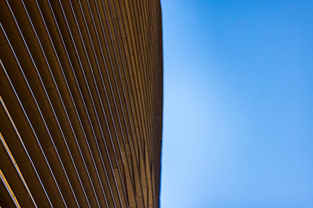 Abstract modern architecture detail with brown horizontal cladding lines against clear blue sky, minimal urban design, contemporary building facade pattern, background concept.