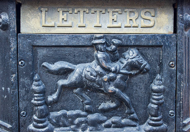 Close-up of a vintage metal mailbox featuring a raised relief of a horse rider and the word “LETTERS”. Weathered cast metal surface with strong texture and historic character.
