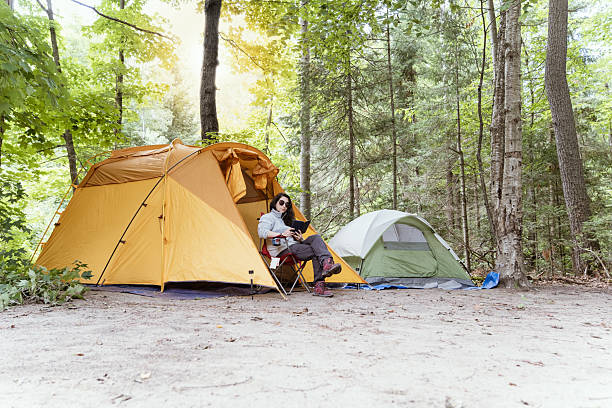 woman sitting reading outside a yellow tent in a campground