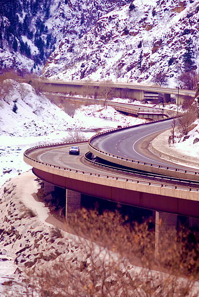 Interstate 70 near Glenwood Springs, Colorado, winds its way through Glenwood Canyon along the Colorado River in winter as snow blankets the ground around it.