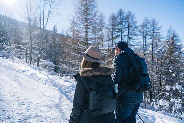 Senior couple walk snowy pathway on sunny winter day, Sauze d'Oulx, Piedmonte