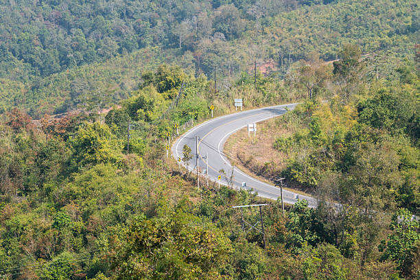 Curve asphalt road with beautiful mountain place background in daytime at rural place of Thailand.