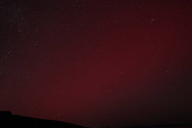 Dark blue sky with stars in the background with Starlink trail and Pleiades.