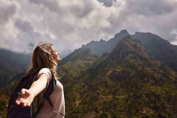 Carefree female hiker enjoying in spring day with her arms outstretched on a mountain. Copy space.
