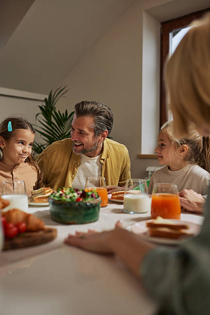 Family breakfast at home with father and two daughters enjoying a cozy morning together