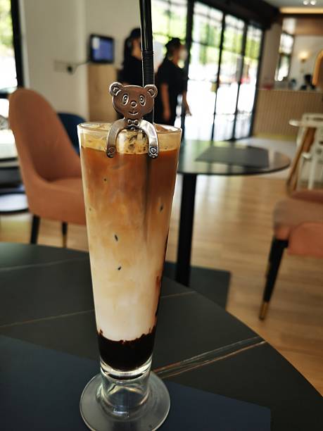 Layered Iced Latte with Decorative Straw in Modern Cafe