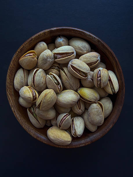 Pistachios in Wooden Bowl on Dark Background